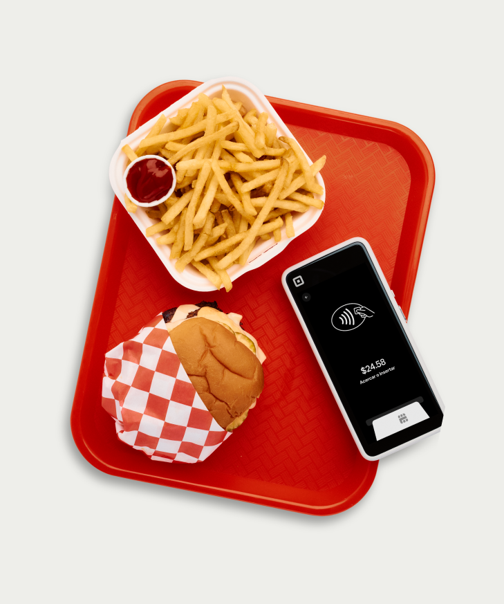 Red fast-food tray with burger, fries, ketchup, and Square Terminal showing contactless total